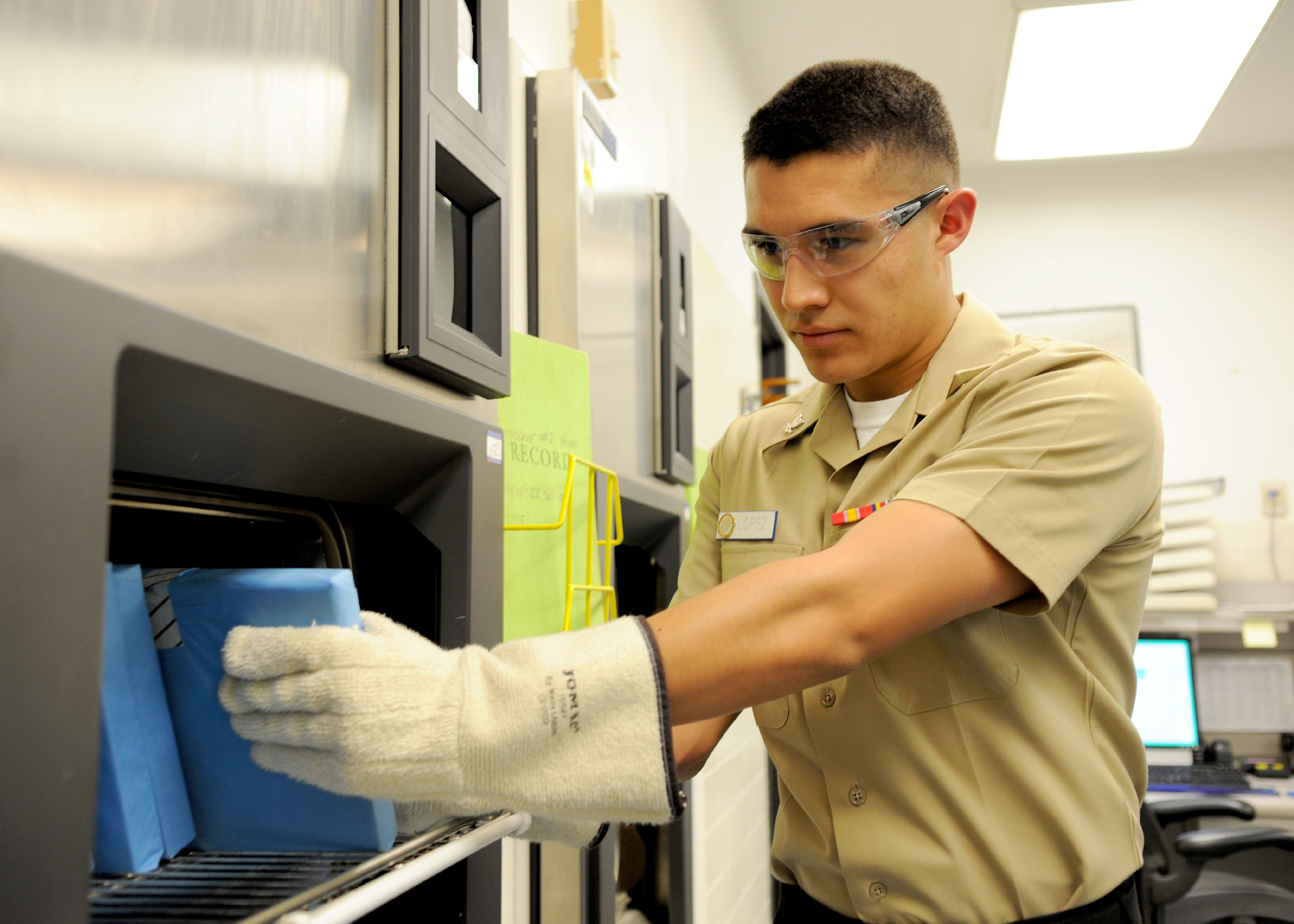 Hospital technician unloading wrapped instruments from an autoclave